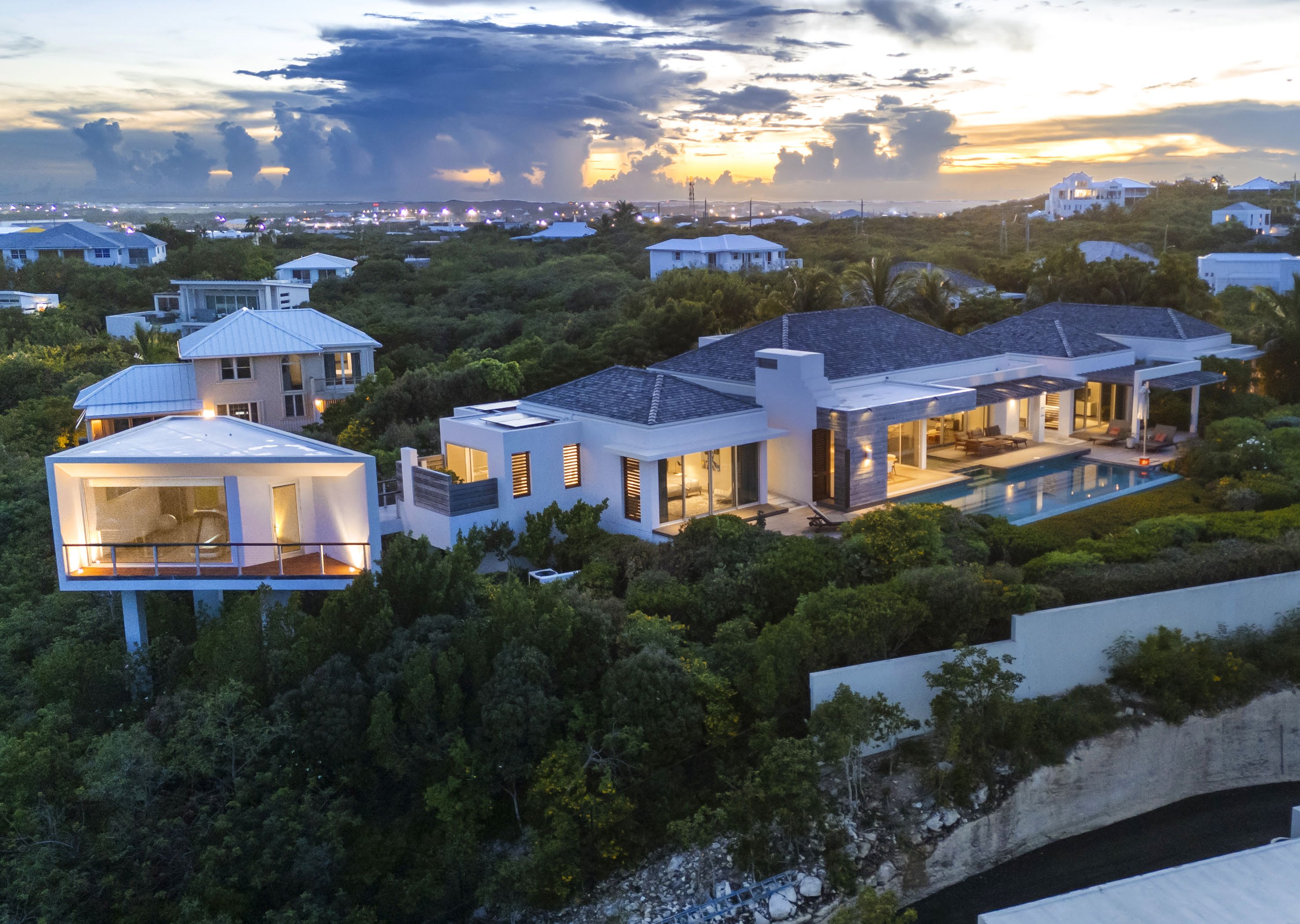 Hillside collection of white architect-designed villas with pools at sunset on Blue Mountain, Turks & Caicos